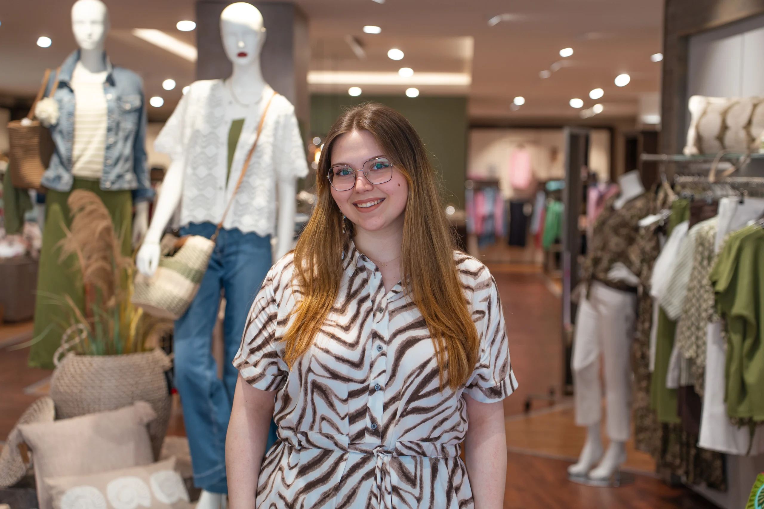 Mitarbeiterin im Modehaus Rieke vor Kleiderständern und Schaufensterpuppen