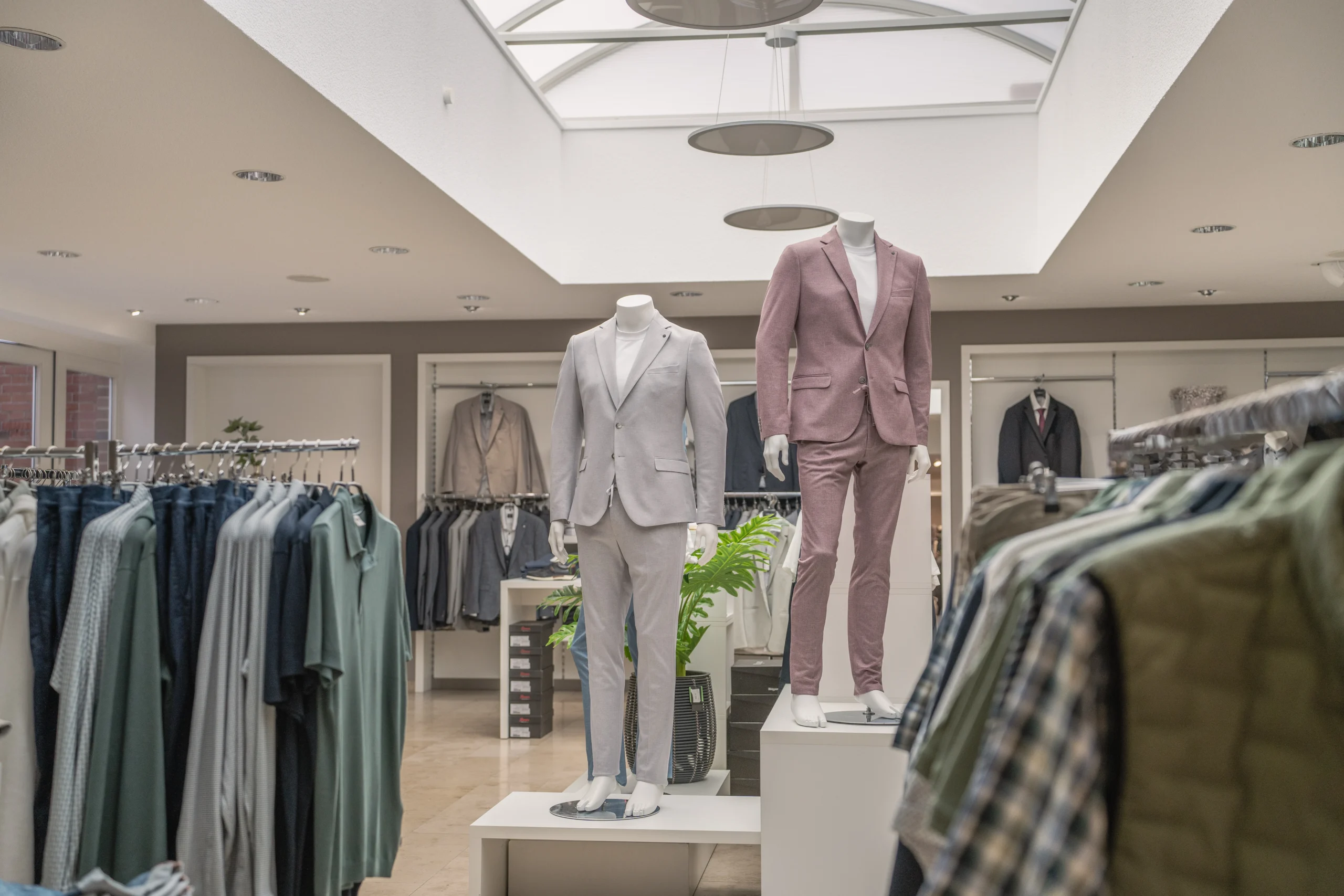 Moderne Herrenmode im Modehaus Rieke auf Kleiderstangen und Podest präsentiert